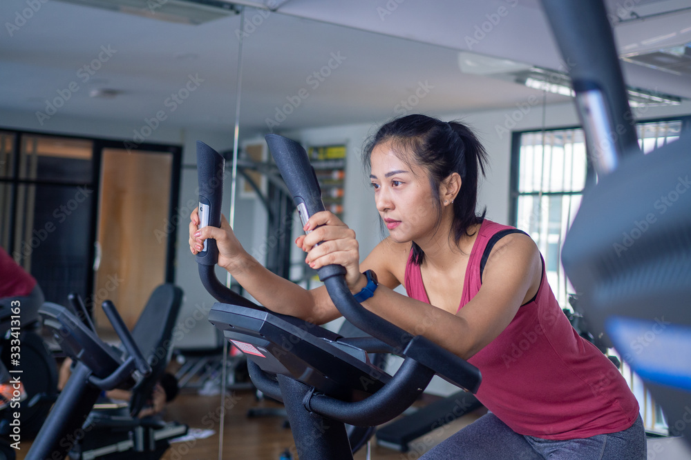 Fototapeta premium Woman electric bicycles in at fitness gym, Young woman workout in gym healthy lifestyle