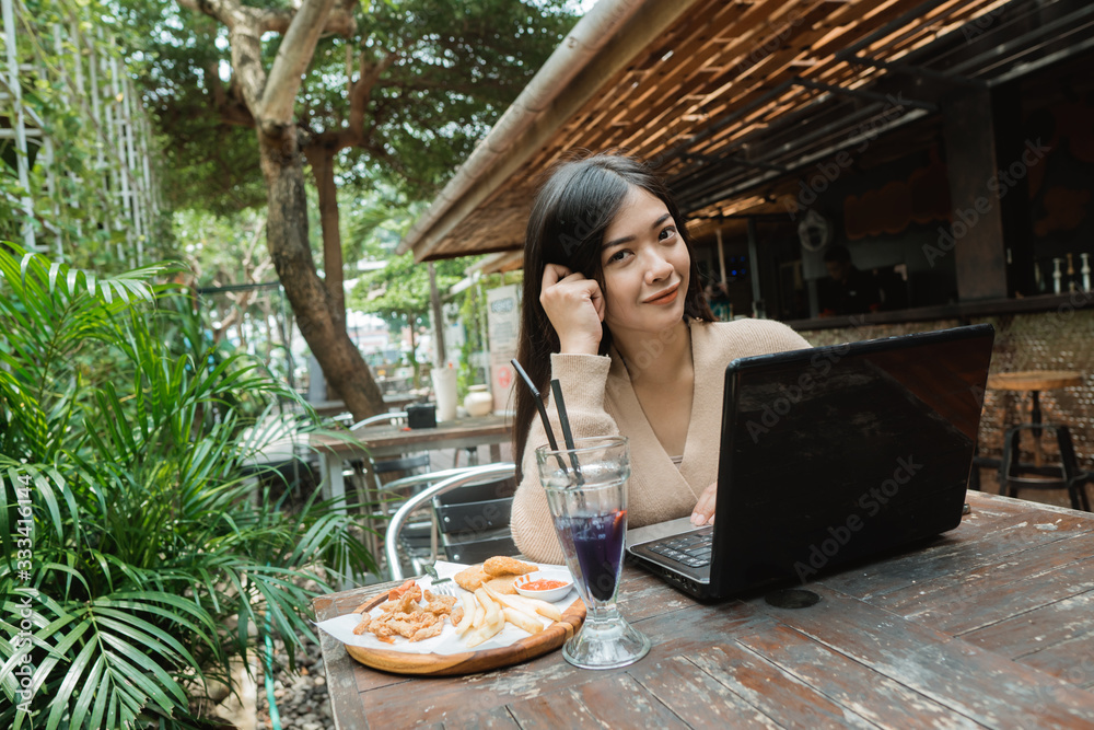 woman enjoy lunch while working on her laptop in coffe shop