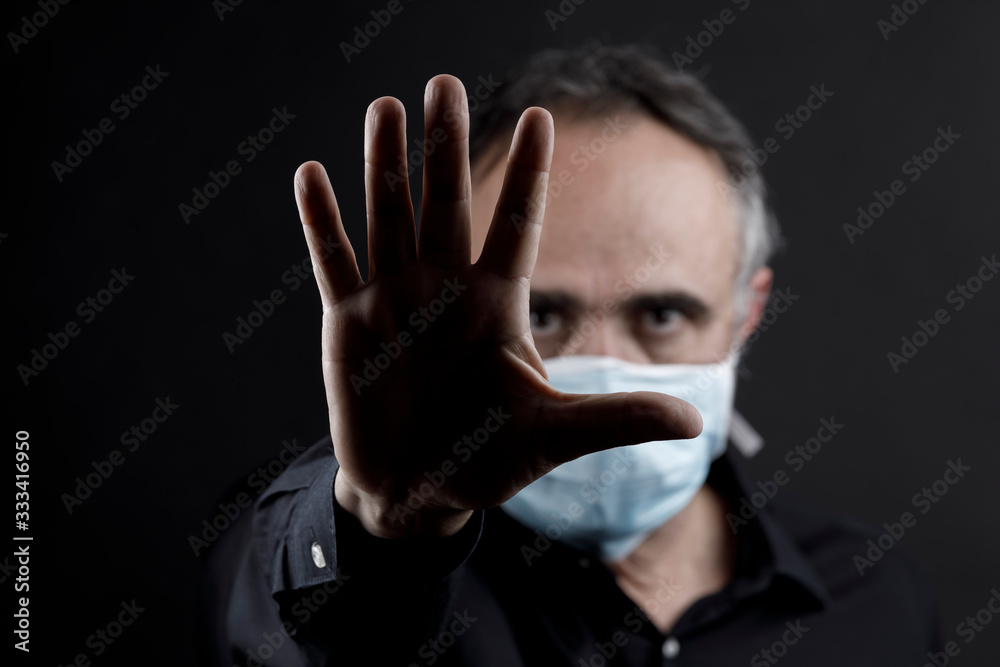 uomo in camicia nera che indossa una mascherina azzurra, isolato su sfondo nero uomo in camicia nera che indossa una mascherina azzurra, isolato su sfondo nero