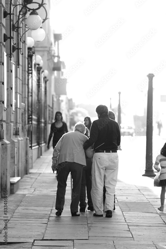 elderly couple supporting oneanother while walkin the streets