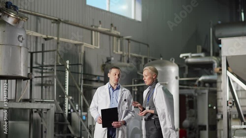 Wallpaper Mural Tilt down medium shot of two quality control experts in white coats, middle aged female and male, talking while examining factory building Torontodigital.ca