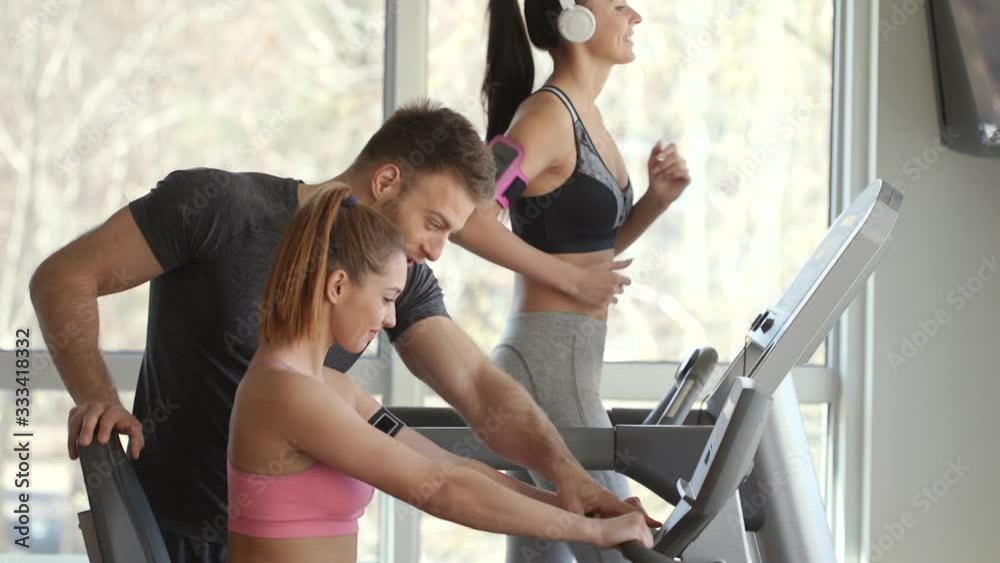 Personal trainer with pretty young woman on cycling machine at the gym Personal trainer with pretty young woman on cycling machine at the gym