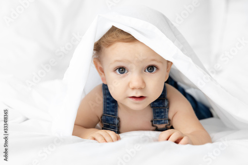 Cute baby hiding under white sheet
