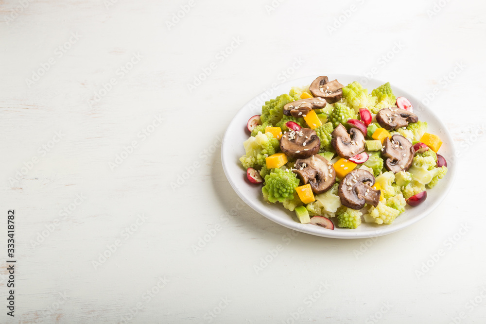 Vegetarian salad from romanesco cabbage, champignons, cranberry, avocado and pumpkin on a white wooden background. side view, copy space. Vegetarian salad from romanesco cabbage, champignons, cranberry, avocado and pumpkin on a white wooden background. side view, copy space.