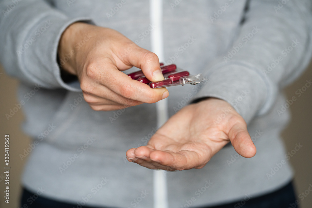 Fototapeta premium Woman's hands taking out a capsule of medication on her hand with the background out of focus.
