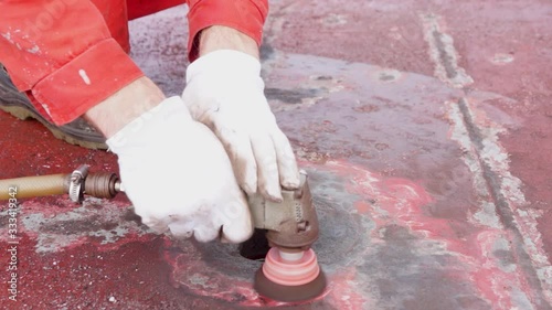 Process of derusting, paint and rust removal by pneumatic grinder from ship deck by vessel crew. Close up. Ship deck maintenance concept. photo