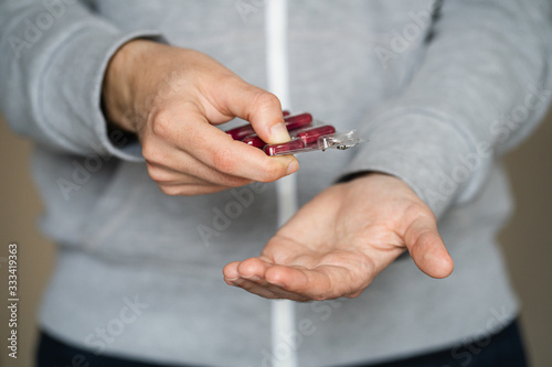 Woman's hands taking out a capsule of medication on her hand with the background out of focus.