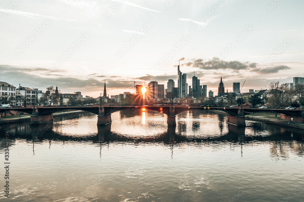 sunlight shines trough Frankfurt skyscrapers at sunset