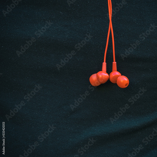 Bright red in-ear headphones on the background of black t-shirt
