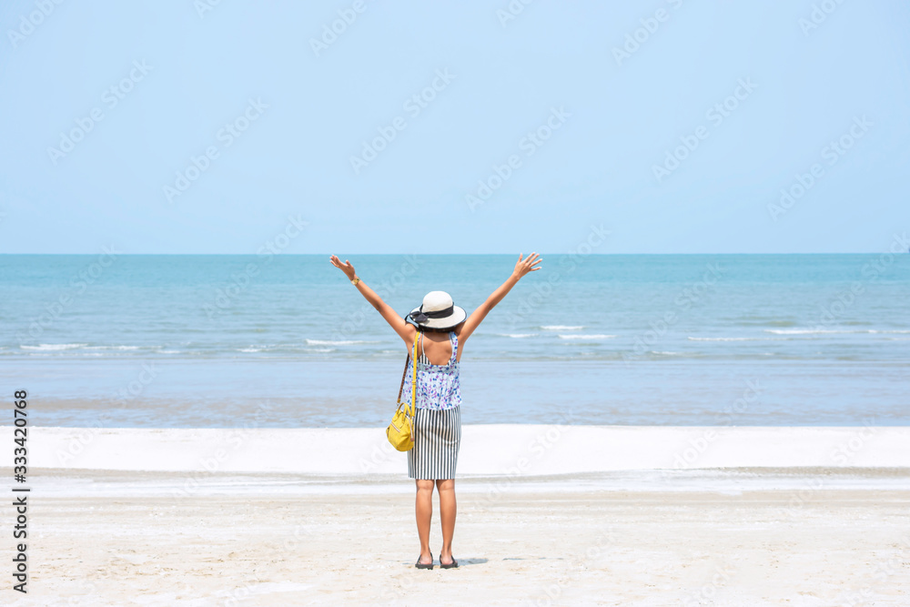 The image behind Asian women raise their arms and wear a hat background sea. The image behind Asian women raise their arms and wear a hat background sea.