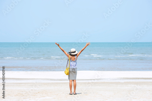 The image behind Asian women raise their arms and wear a hat  background sea.