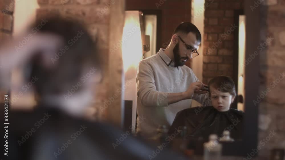 Hairdresser cutting hair of child in Barbershop Hairdresser cutting hair of child in Barbershop