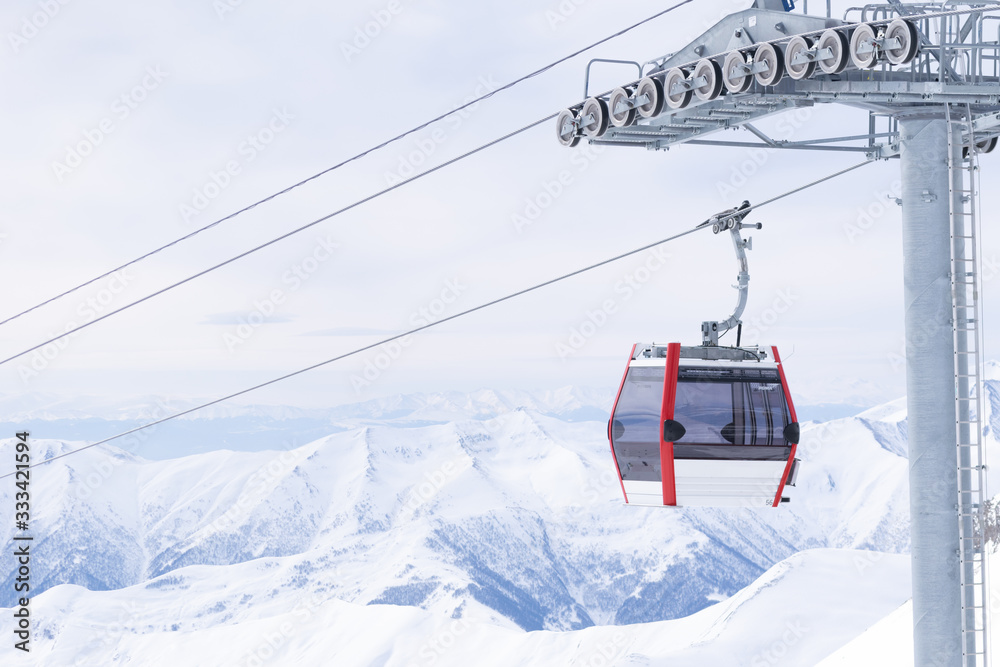 Empty white/red closed ski lift cabin with no people and white dramatic mountains in the backround. End of season concept.Gudauri. Georgia.2020