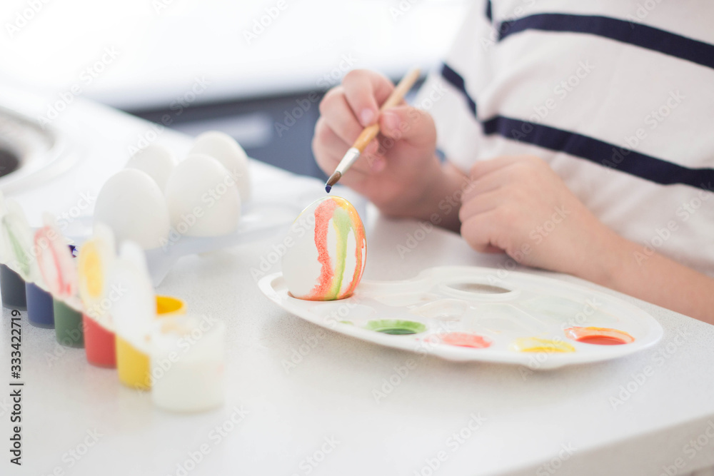 a child paints eggs with watercolors and gouache waits for Easter and plays