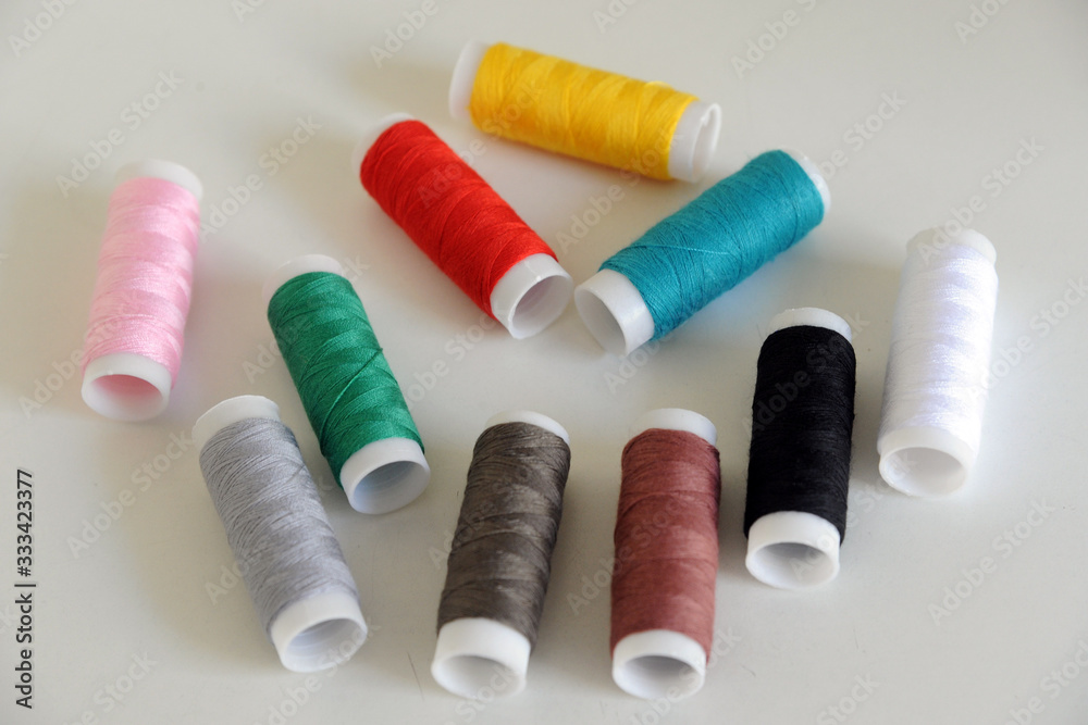 Accessories for tailoring on white table - Scissor , scissors, buttons, needle and thread, spools of colored threads Accessories for tailoring on white table - Scissor , scissors, buttons, needle and thread, spools of colored threads