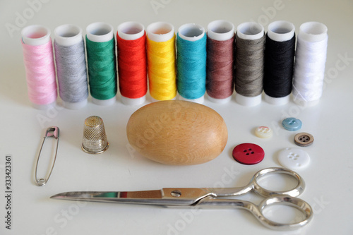 Accessories for tailoring on white table - Scissor , scissors, buttons, needle and thread, spools of colored threads