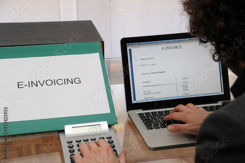 Milan , Italy january 5,2018 ( electronic )  e - invocing - secretary makes an electronic bill with calculator and laptop  in the office - online tax return - business consultant