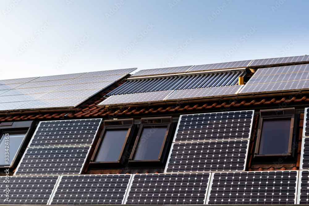 Fototapeta premium House with solar panels and solar panels for water heating on roof - regenerative energy system electricity generation