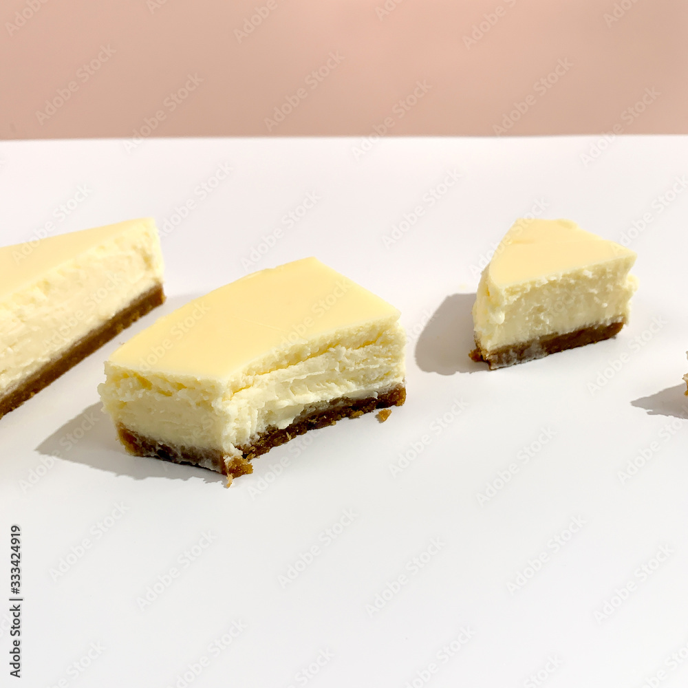 Bright pieces of cheesecake on white pink background