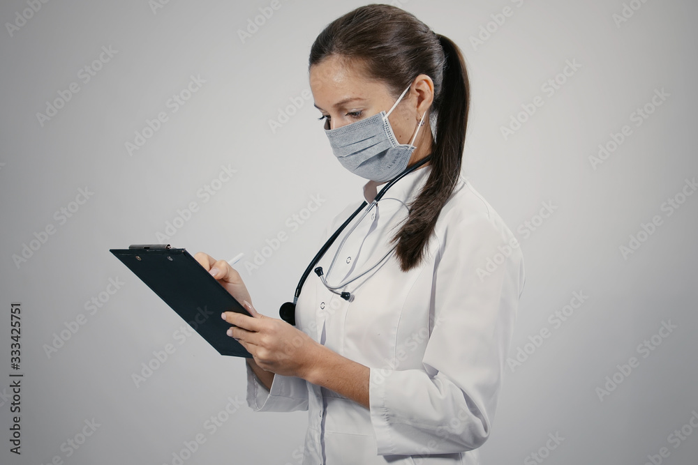 Lovely female doctor in a white medical coat general practitioner physician with a phonendoscope writing notes making patients appointments schedule in notepad Lovely female doctor in a white medical coat general practitioner physician with a phonendoscope writing notes making patients appointments schedule in notepad