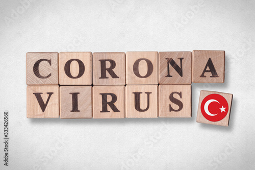 Wooden blocks with flag of Turkey and letters spelling CORONAVIRUS on white paper texture background. Novel Coronavirus (2019-nCoV) concept, for an outbreak occurs in Turkey.