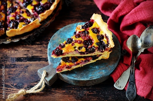 Tarte with berries and sour cream fill on a dark wooden background. rustic