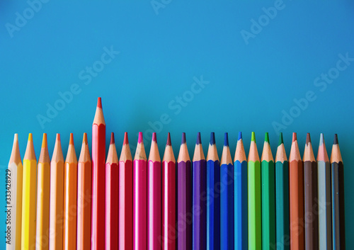 Set of colored pencils on a blue background and the red colored pencil predominates