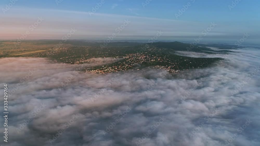 Forward movement of an aereal view with a big settlements on the hills covered with fog on sunrise. Forward movement of an aereal view with a big settlements on the hills covered with fog on sunrise.