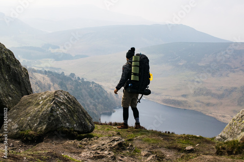 Viajero cargado con mochila grande contemplando un paisaje desde las alturas en Irlanda photo