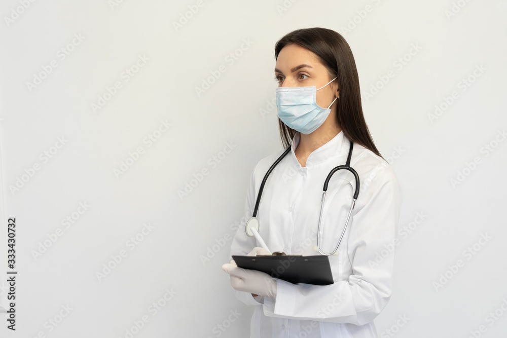 Female doctor in a protective medical mask and gloves, writes the diagnosis to the clients card Female doctor in a protective medical mask and gloves, writes the diagnosis to the clients card