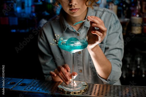 woman bartender professionally adds cocktail ingredient using pipette