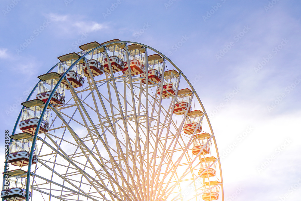 Part of white ferris wheel against blue cloudy sky background. Close-up of swirling big wheel against of blue cloudy sky.     