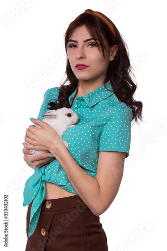 Beautiful brunette woman holding a white, fluffy rabbit. A pet. Dressed in a mint shirt with chelma on his head. Hike to the vet. Modern image. Isolate, white background. photo