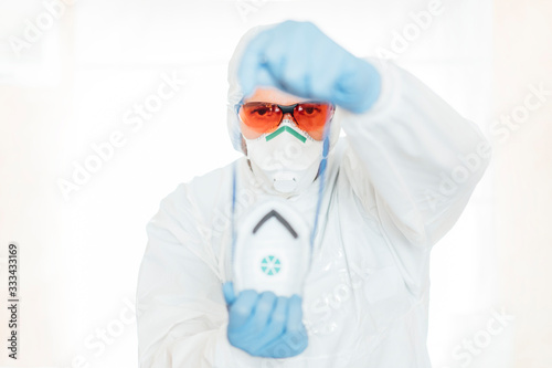 Man in NBC anti-contagion clothing puts on a protective mask. photo