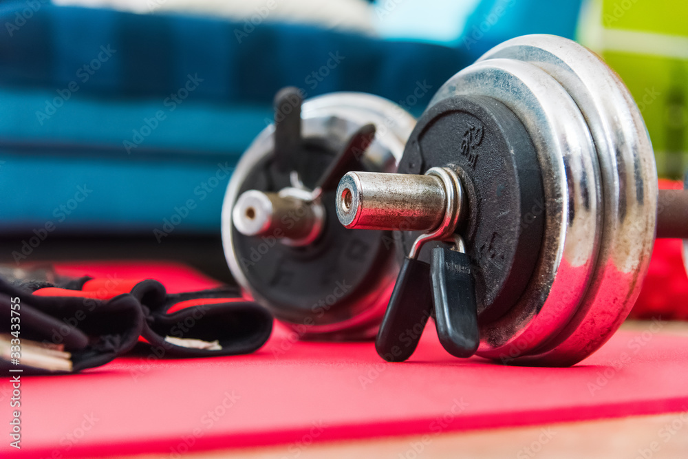 Dumbbells and training gloves on a yoga mattress Dumbbells and training gloves on a yoga mattress