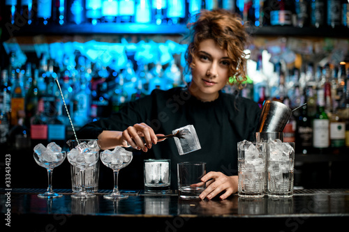Several glasses with ice stand on bar counter
