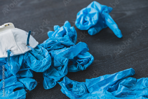 Pile of used sterile blue gloves and face mask lies in  on a floor. Health protection prevention during flu virus outbreak and coronavirus epidemic.