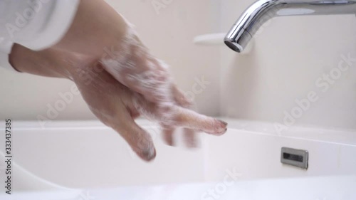 woman washing her hands properly with plenty of soap in her home sink without wasting water photo