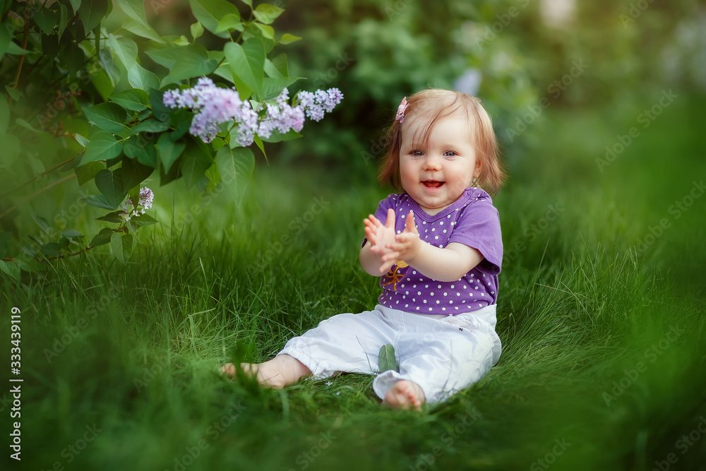 little girl crawling sitting in the grass at the lilac Bush, spring has come, cute baby, may, flowering little girl crawling sitting in the grass at the lilac Bush, spring has come, cute baby, may, flowering