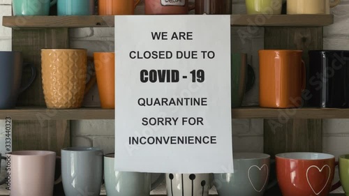 Zoom in shot of biohazard concept of living in a new reality of coronavirus epidemic hysteria cafe owner sticks advertisement on quarantine measures to contain virus pinned on shelf with colorful mugs