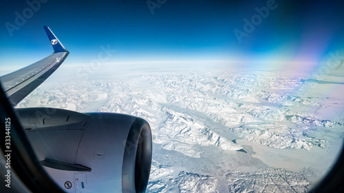 Flying over Greenland in plane. Aerial view of North pole and massive ice fields. View from air plane window.