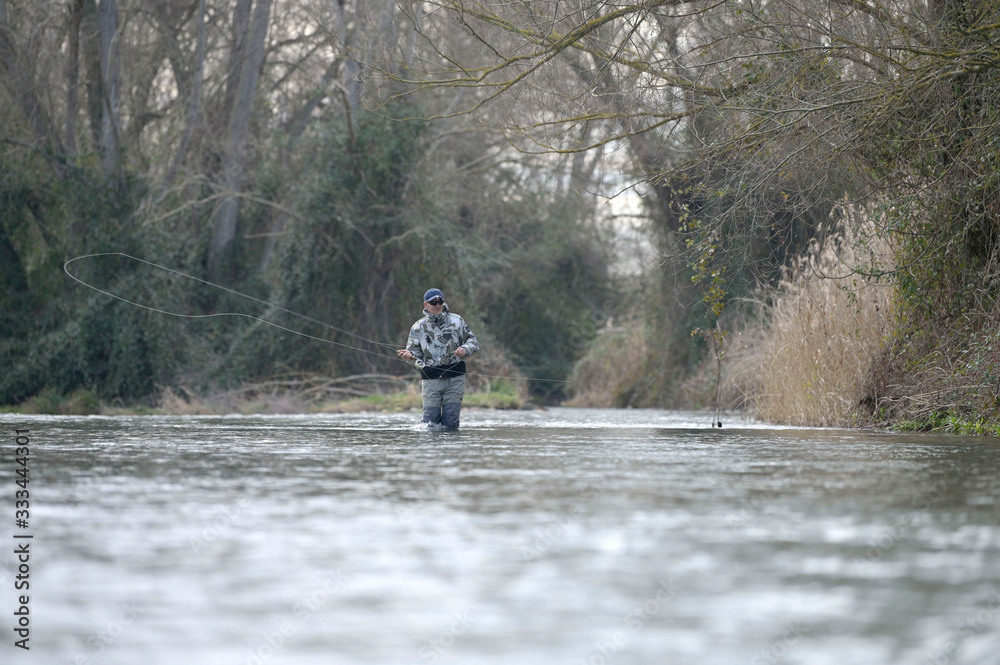 fly fisherman in river in winter