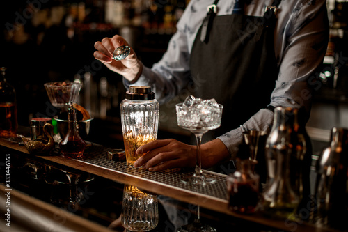 Barman at bar preparing cocktail in glassy shaker