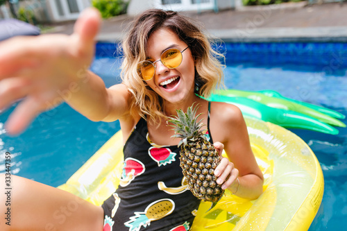 Fototapeta Amazing short-haired girl in trendy glasses swimming in pool