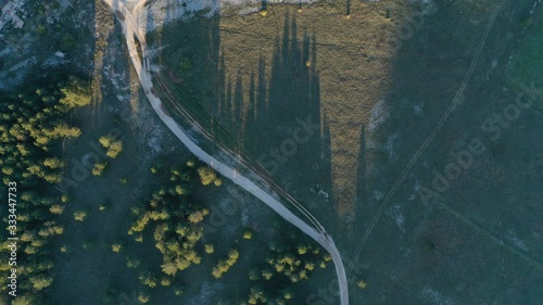 Aerial view of Rural landscape. Rural road near fir tree forest. Countryside, nature. Summer sunset. Beautiful shadows. Grahovo, Montenegro. © dimabucci