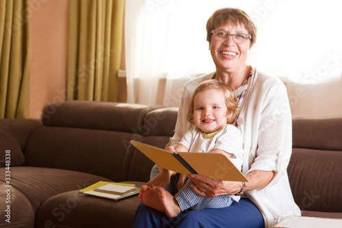 Grandmother reading a tale to her baby granddaughter. Family Reading Leisure. Quality Time. Happy Family having fun playing at home.   