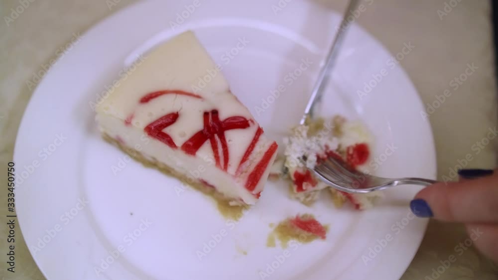 Up view of cheese cake on white plate. Woman cut in with knife and take a piece with a fork. Delicious favorite pastry. Up view of cheese cake on white plate. Woman cut in with knife and take a piece with a fork. Delicious favorite pastry.