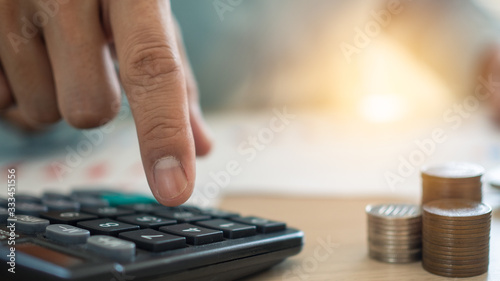 The man's finger that presses the calculator to calculate and analyze income and expenses the growth of coins and financial costs, wisely and prudently, the concept of investment ,savings and debt photo