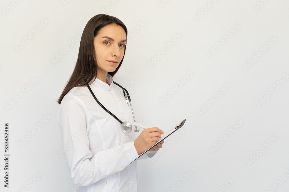 Friendly female doctor, writes the diagnosis to the clients card, a stethoscope on his neck Friendly female doctor, writes the diagnosis to the clients card, a stethoscope on his neck