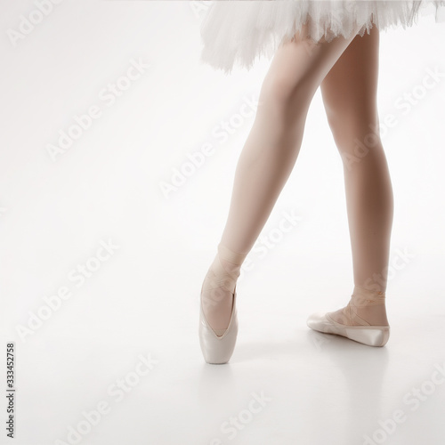 Legs of a ballerina on a white background in pointe shoes